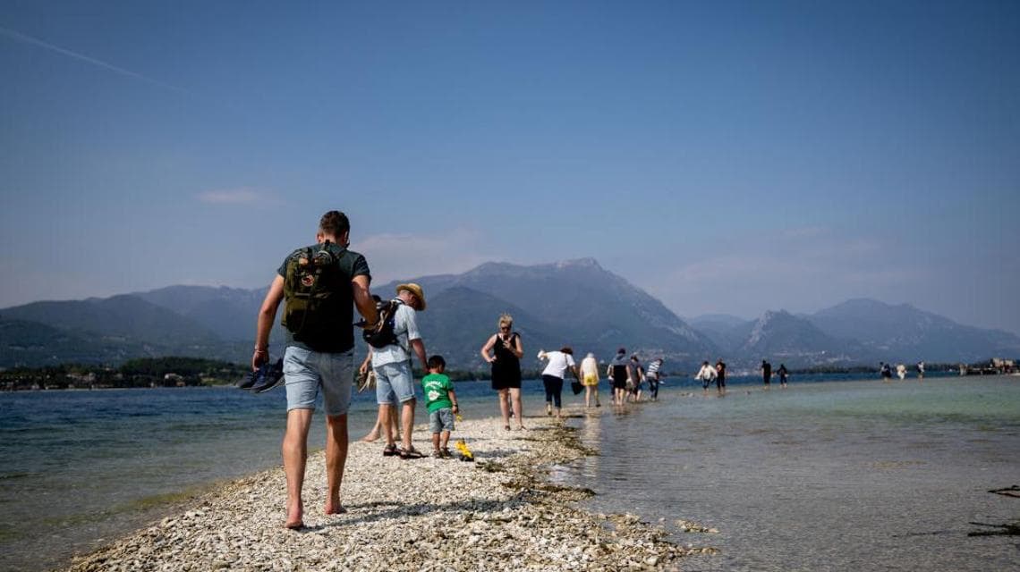 Visitatori a piedi sull'Isola di San Biagio, nel Lago di Garda prosciugato dalla siccità (28 aprile 2023, Manuel Romano/NurPhoto)