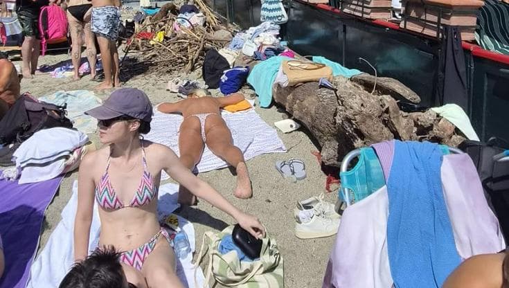 La legna della spiaggia privata accatastata tra i bagnanti su quella pubblica, rivolta a Paraggi