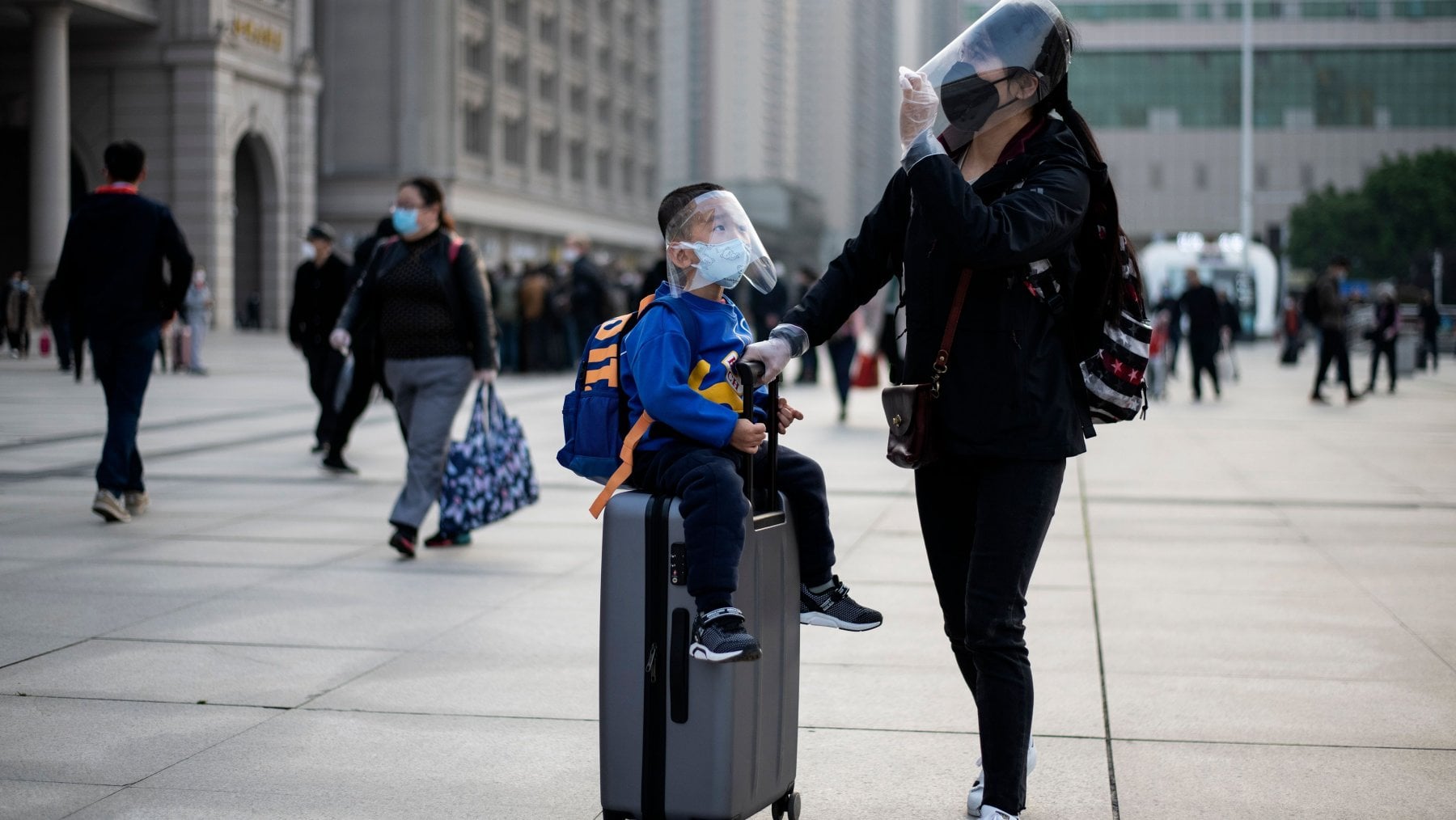 Una donna e il figlio arrivano alla stazione di Wuhan per lasciare la citt&agrave;, 8 aprile 2020 (Noel Celis/AFP)