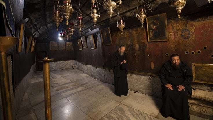 Sacerdoti in preghiera nella Grotta della Nativit&agrave; a Betlemme. Foto EPA/ATEF SAFADI
