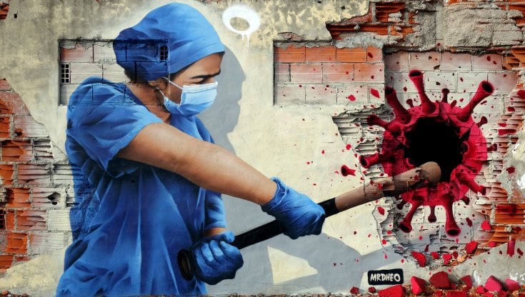 Un&rsquo;infermiera colpisce il coronavirus nel murale di MrDheo a Vila Nova de Gaia in Portogallo (&copy; MrDheo)