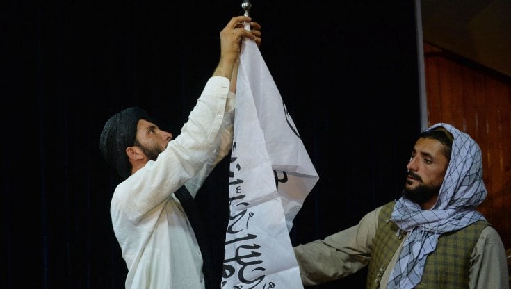 Afghanistan, talebani sistemano la bandiera in occasione della prima conferenza stampa a Kabul