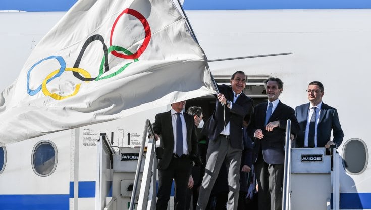 Il sindaco di Milano Beppe Sala sbarca dall'aereo con la bandiera a Cinque Cerchi