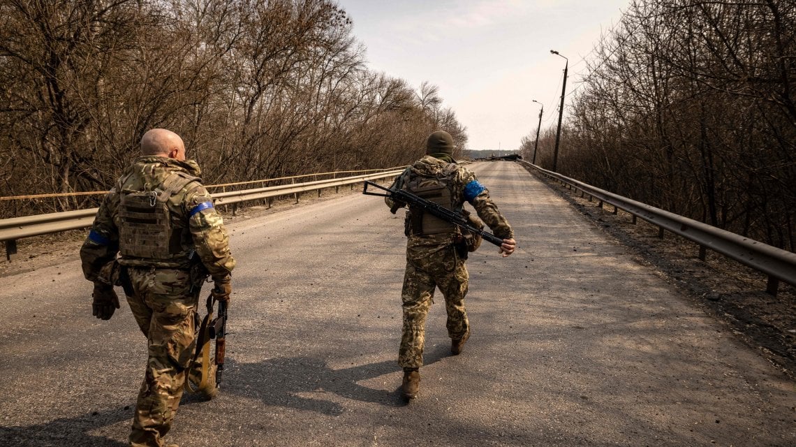 Ukrainian soldiers walk toward a bridge destroyed by the Russian army in the town of Rogan, east of Kharkiv