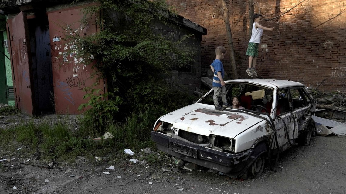 Children play on a destroyed car in a residential area of Mariupol on May 29, 2022, amid the ongoing Russian military action in Ukraine