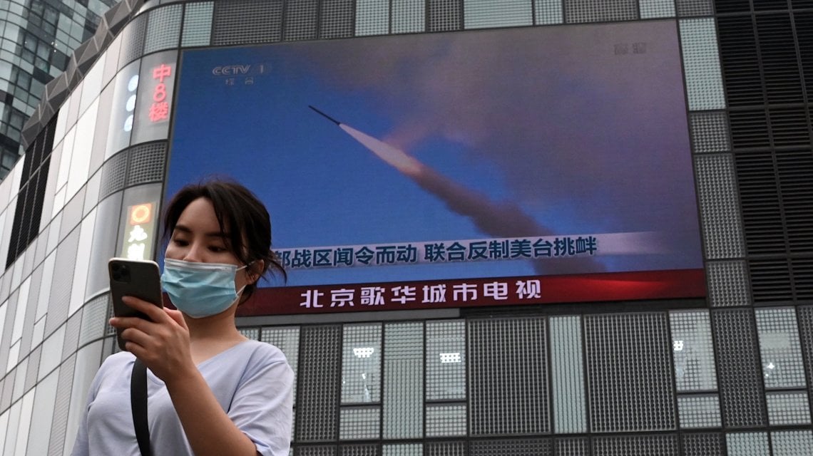 Pechino, una donna di fronte a un maxi schermo che mostra le esercitazioni militari intorno a Taiwan