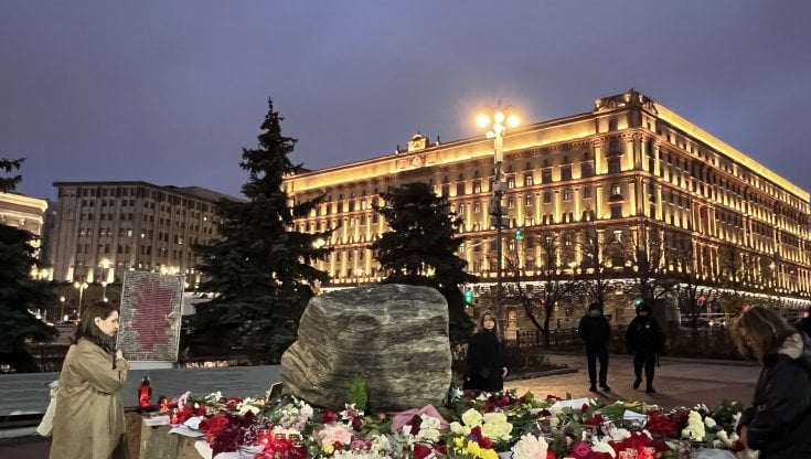 Fiori e biglietti coi nomi delle vittime di Stalin sulla pietra Solovetskij in piazza Lubjanka. Sullo sfondo, la sede dell'Fsb, ex Kgb