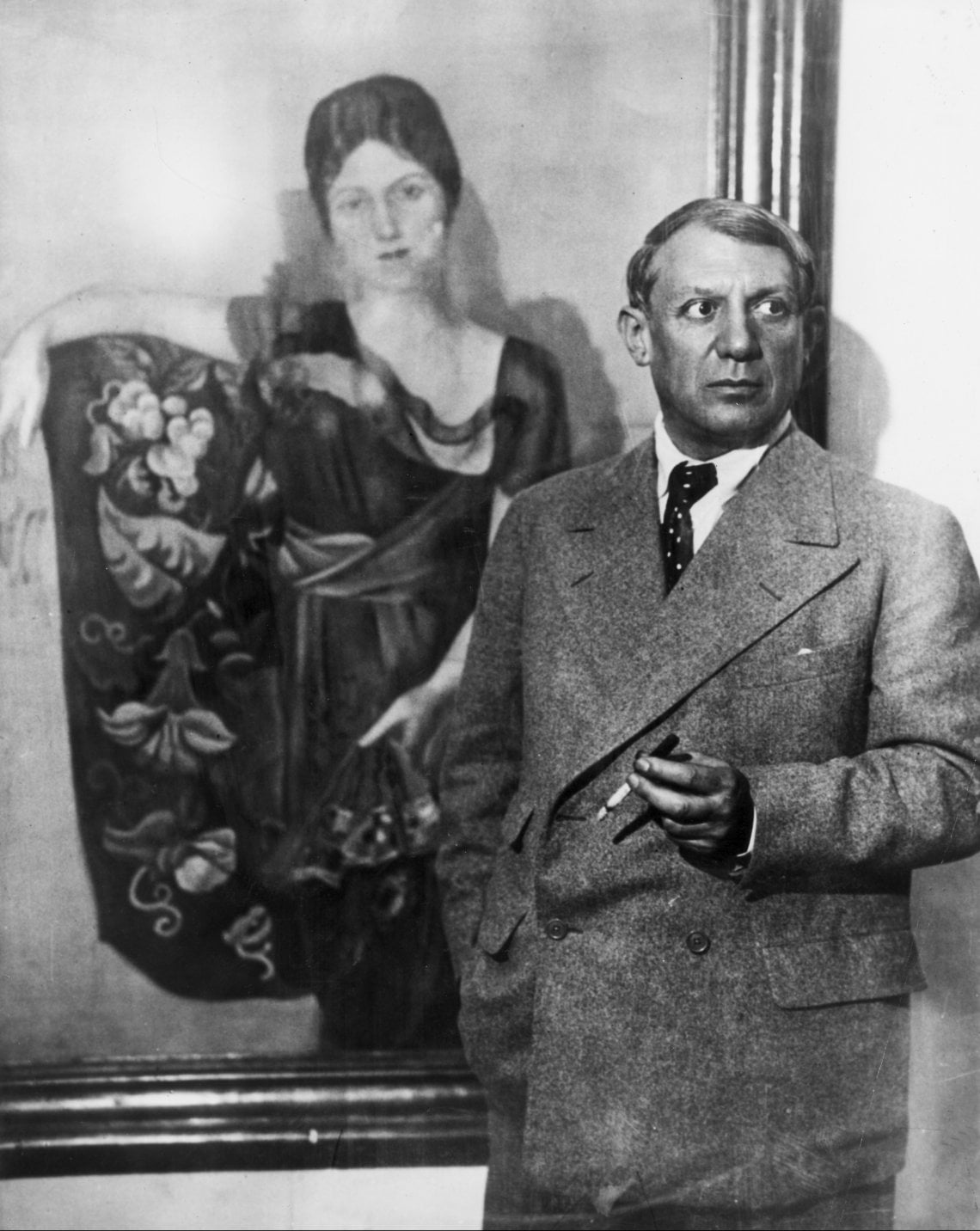 Pablo Picasso fotografato davanti al ritratto della moglie Olga
