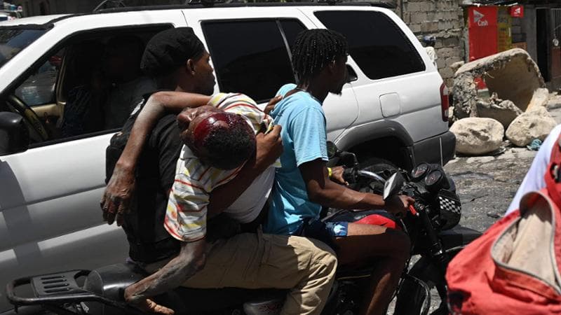 Un uomo ferito durante uno scontro tra bande a Port-au-Prince portato in moto in ospedale
