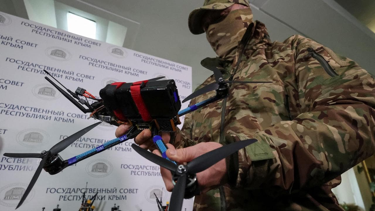 Crimea, un militare russo con in mano un drone assemblato da volontari
