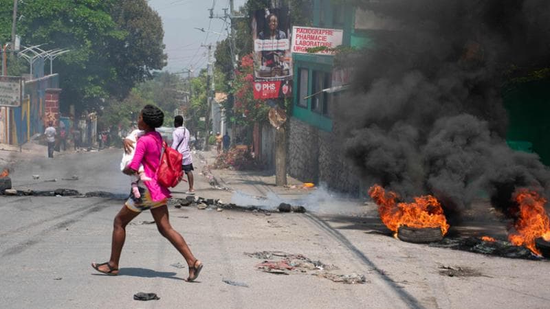 Port-au-Prince (Haiti), 20 marzo: una donna con un bambino in braccio si mette al riparo dagli scontri