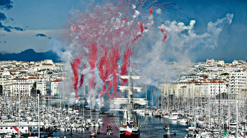 French 19th-century three-masted barque Belem (C) arrives at the Vieux-Port (Old Port) as red white and blue fireworks are fired, during the Olympic Flame arrival ceremony, as part of its journey ahead of the Paris 2024 Olympic and Paralympic Games, in Marseille, southeastern France, on May 8, 2024. The transfer of the flame onshore from a 19th-century tall ship will mark the start of a 12,000-kilometre (7,500-mile) torch relay across mainland France and the country's far-flung overseas territories. (Photo by Sylvain THOMAS / AFP)