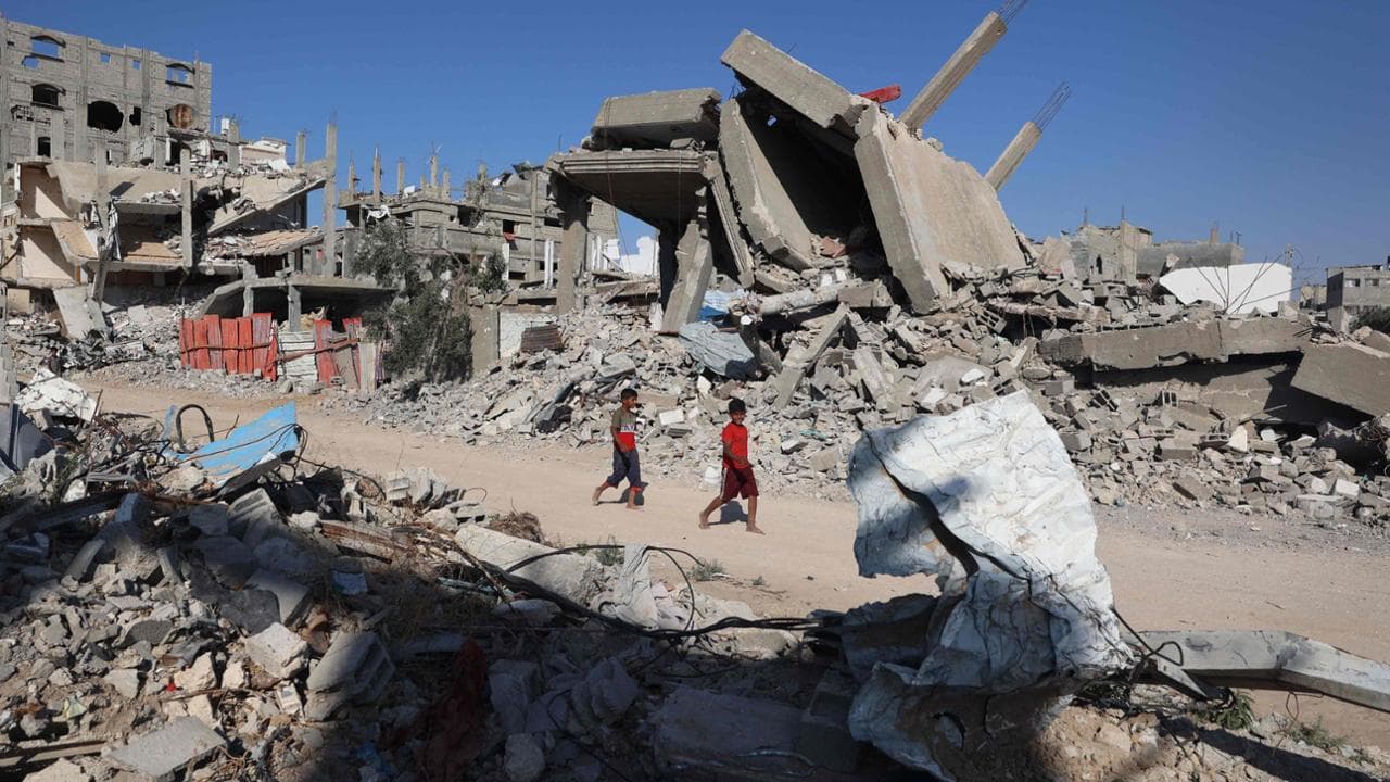 Palestinian boys walk past destroyed buildings al-Bureij camp in the central Gaza Strip on June 2, 2024, amid the ongoing conflict between Israel and the Palestinian Hamas militant group. (Photo by Eyad BABA / AFP)