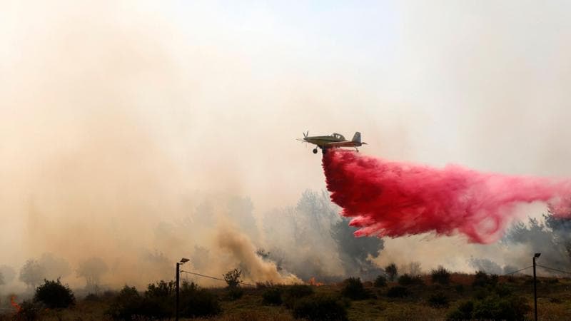 A firefighting aircraft releases flame retardant to extinguish fires caused by rockets launched from southern Lebanon which landed on the outskirts of Safed, in the upper Galilee, on June 12, 2024. Lebanon's Hezbollah, a Hamas ally, and Israel have been trading near-daily fire since the Gaza war was trigged by the Palestinian militant group's October 7 attack on southern Israel. (Photo by Jalaa MAREY / AFP)