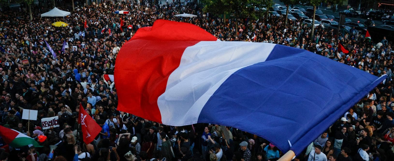 A protester hold a French flag as people gather at the Place de la Republique after partial results in the second round of the early French parliamentary elections, in Paris, France, July 7, 2024. REUTERS/Abdul Saboor