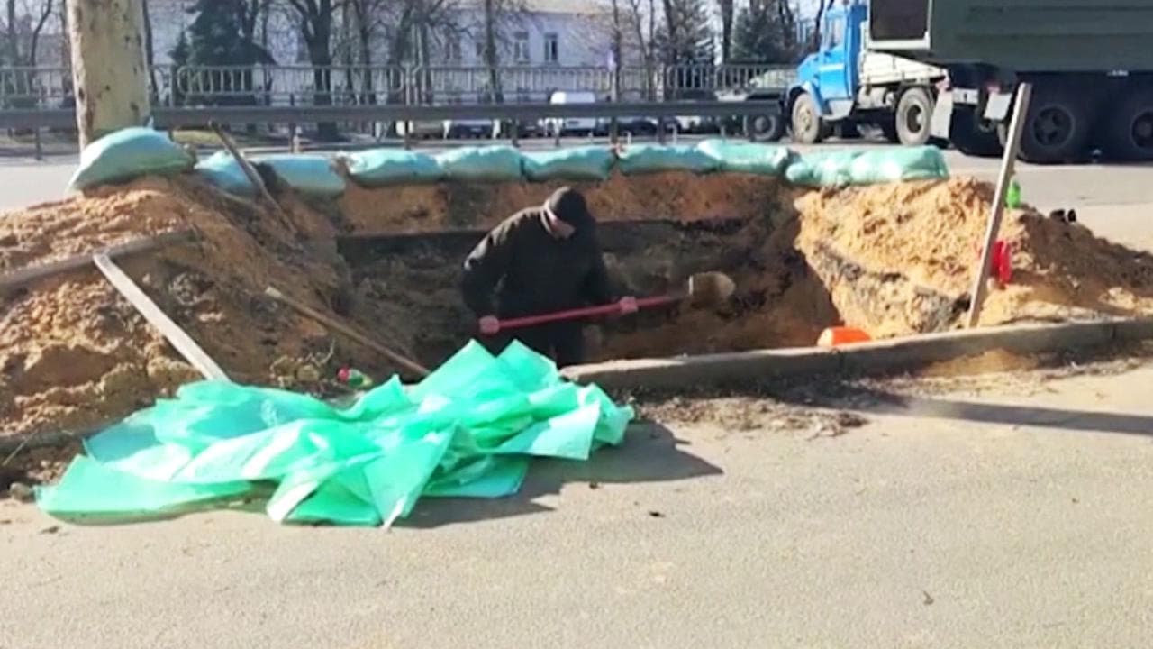 Ucraina, un uomo scava una trincea in una strada principale di Kiev