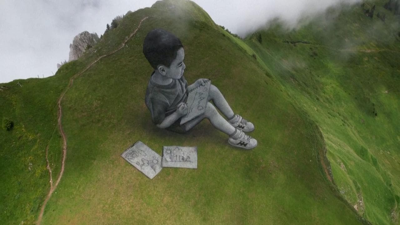 Due bimbi disegnano il loro mondo: le spettacolari opere di Saype sui pendii delle montagne svizzere