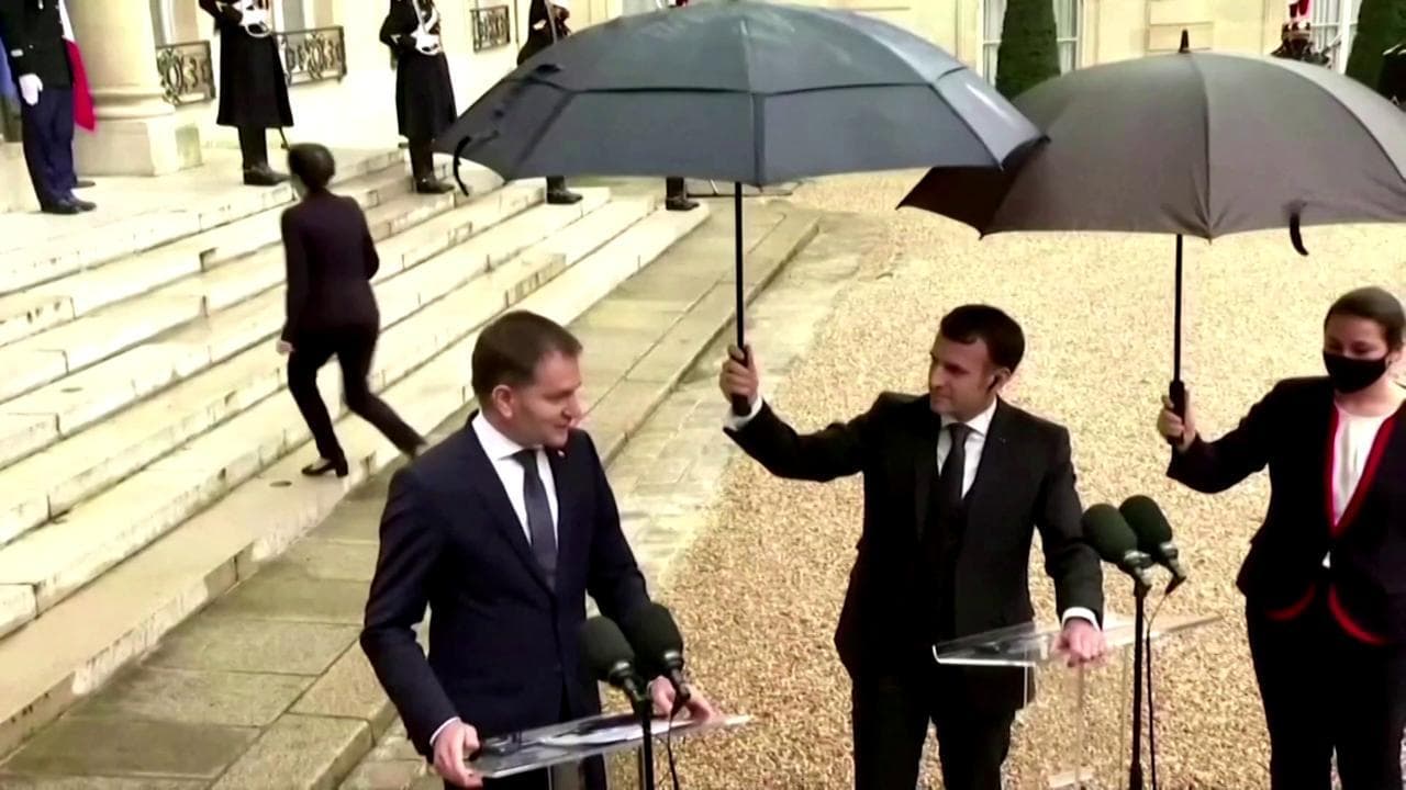 Parigi, evento sotto la pioggia all'Eliseo e il presidente Macron si improvvisa 'ombrellino'