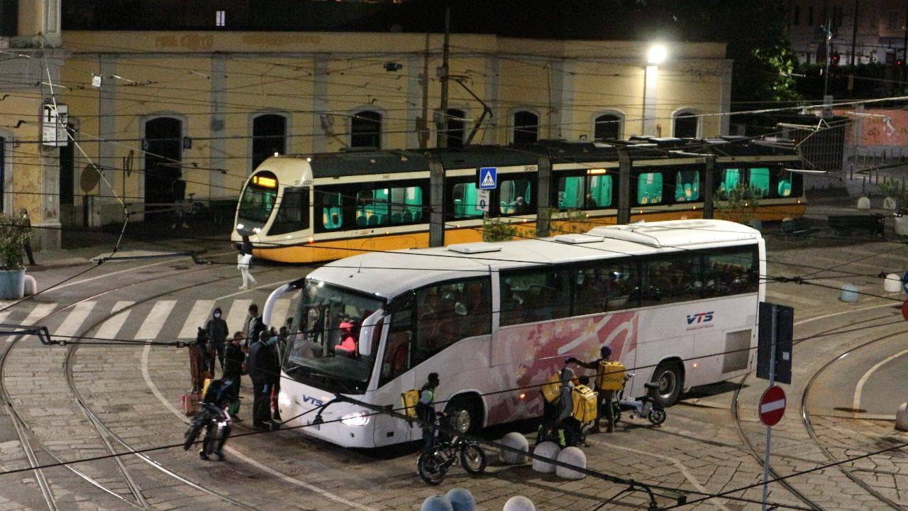 Milano, la lotta dei rider a mezzanotte per salire sulla corriera che li porterà a casa nell'hinterland