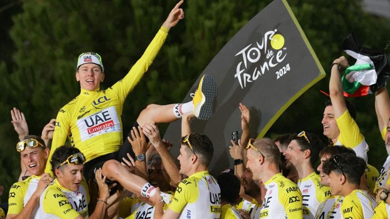 (FILES) UAE Team Emirates team's Slovenian rider Tadej Pogacar celebrates his overall victory on the podium with teammates and staff after the 21st and final stage of the 111th edition of the Tour de France cycling race, a 33,7 km individual time-trial between Monaco and Nice, on July 21, 2024. (Photo by Thomas SAMSON / AFP)