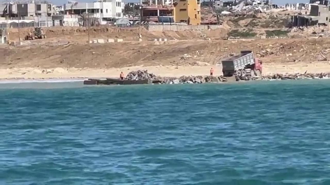Gli aiuti di Open Arms sbarcano davanti a Gaza City: sullo sfondo le macerie della città fantasma