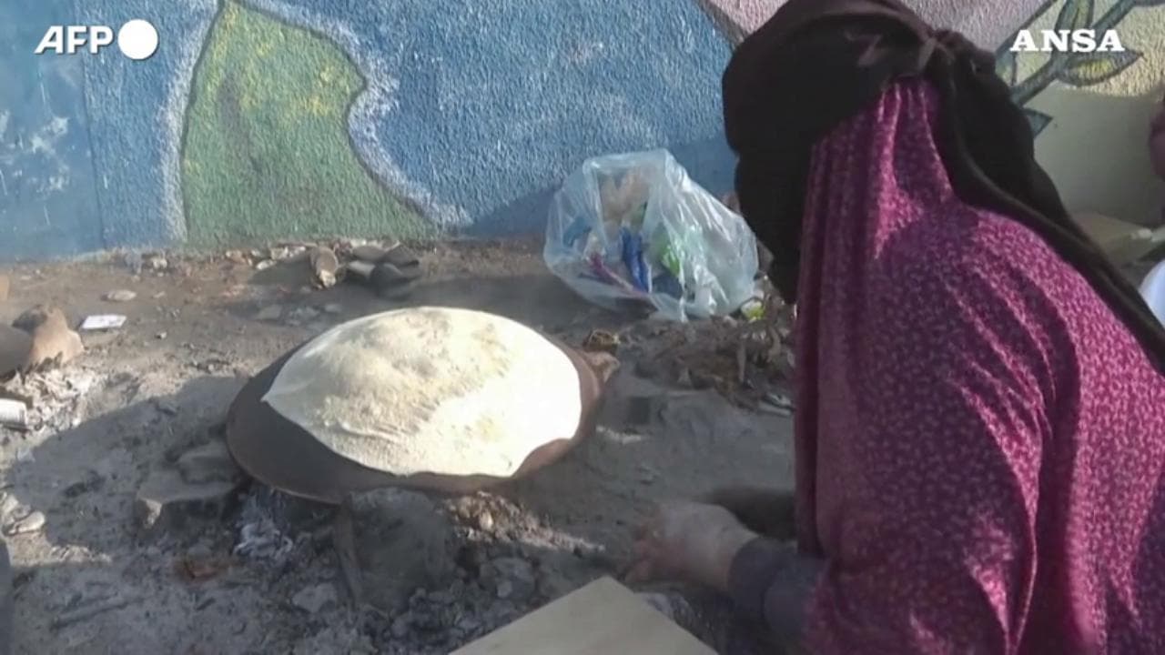 Sopravvivere a Gaza, la mamma cuoce il pane bruciando giornali