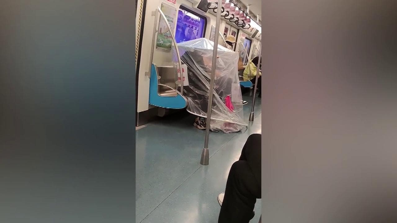 Allarme Covid in Cina, nel metrò c'è chi viaggia coprendosi con un telone di plastica