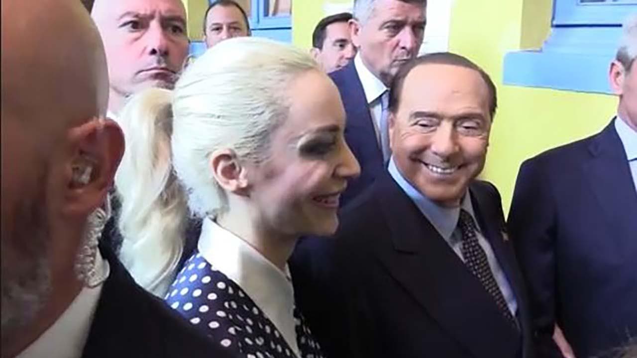 Elezioni, Berlusconi al voto mano nella mano con Fascina alla quale chiede: "Ma tu voti qui?"