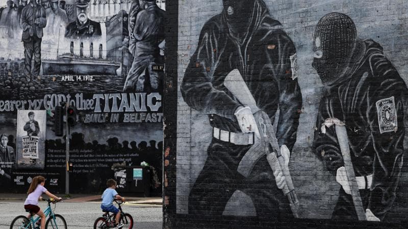 Bambini in bici sotto i murales protestanti a Belfast