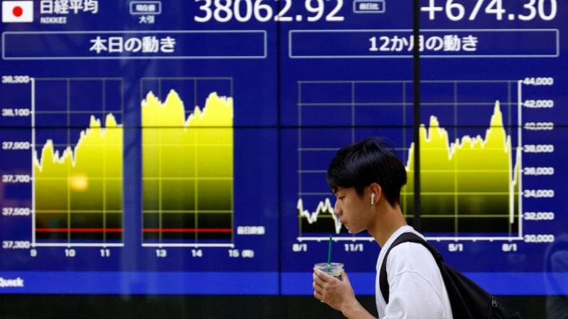 epa11556317 A passerby walks past a stock market indicator board in Tokyo, Japan, 20 August 2024. The Nikkei Stock Average gained 674.30 points, or 1.80 percent, to close at 38,062.92.  EPA/FRANCK ROBICHON