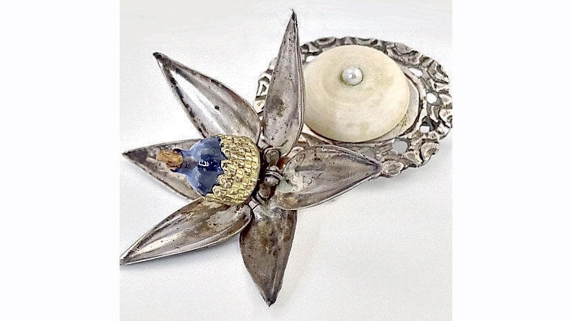 Spagna (1900), spilla in argento con bottone in osso e pendente; i cinque petali mobili del fiore hanno come pistillo un micro flacone in vetro blu