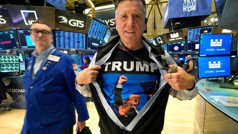 Trader Walter Lundon shows off his shirt featuring US President-elect Donald Trump, on the floor of the New York Stock Exchange (NYSE) in New York City on November 6, 2024. Wall Street stocks surged in opening trading on Wall Street Wednesday after US voters sent Donald Trump back to the White House and delivered him a Republican Senate. Major indices were up 1.8 percent or more in the early going as hopes about expected tax cuts and regulatory easing more than offset worries about higher tariffs. (Photo by TIMOTHY A. CLARY / AFP)