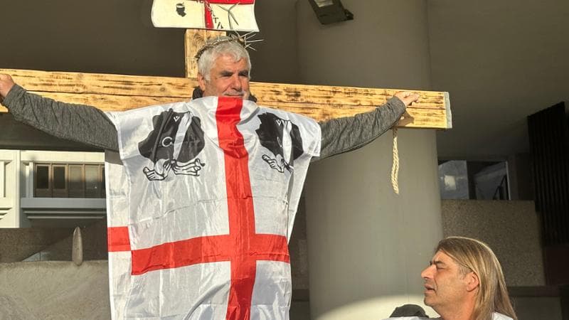 Sardegna, la battaglia contro l’eolico arriva in Regione: manifestanti sulla croce con la bandiera dei quattro mori