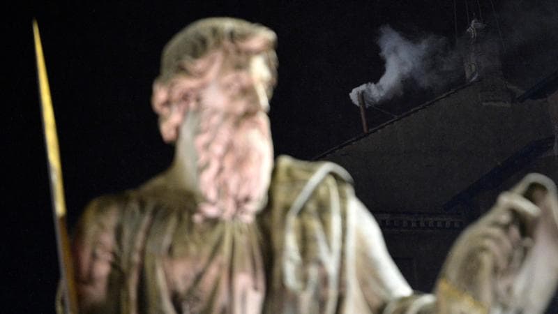 Roma, 13 marzo 2013: dietro una statua di piazza San Pietro, la fumata bianca annuncia l'elezione di José Mario Bergoglio. Foto JOHANNES EISELE/AFP via Getty Images