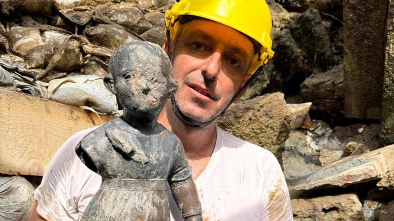 Un archeologo mostra la scultura&nbsp;di bronzo del bambino con la palla
