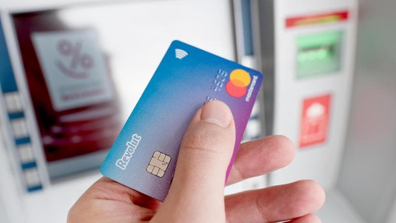 2A9BNHJ Wroclaw, Poland - NOV 06, 2019: Revolut debit card in hand, ATM in background. Revolut Ltd is a UK financial technology company that offers banking se