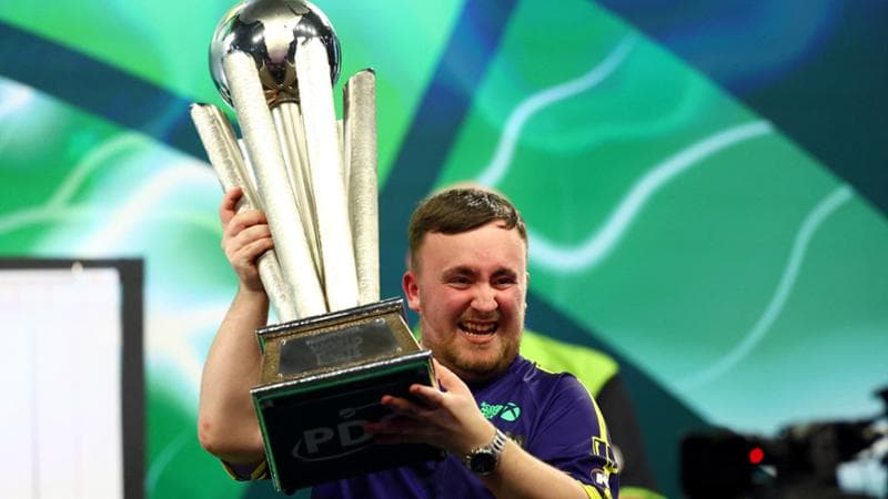 Luke Littler festeggia con il trofeo di campione del mondo di freccette