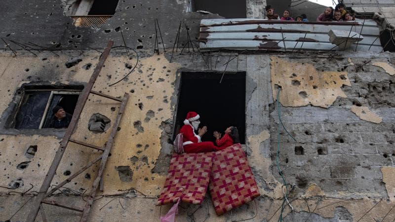 Khan Younis, Striscia di Gaza, 5 gennaio: un Babbo Natale gioca con i bambini tra gli edifici distrutti
