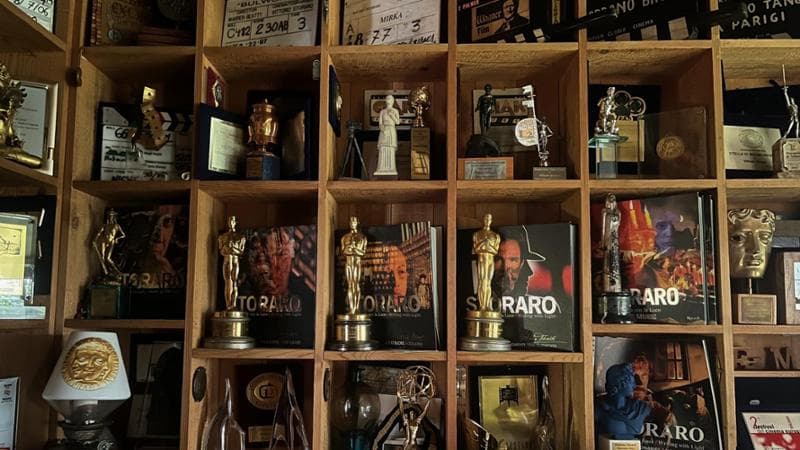 Gli scaffali di casa Storaro dove l’autore della cinematografia (in basso, 84 anni) tiene i suoi premi. Ha vinto tre Oscar: per Apocalypse Now (1980), Reds (1982) e L’ultimo imperatore (1988). Paolo di Paolo