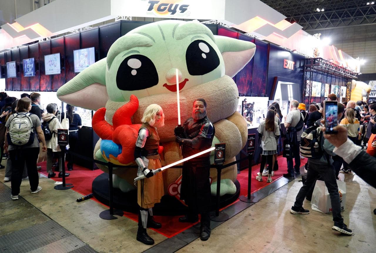 Cosplayer davanti a un Grogu gigante durante la Star Wars Celebration
