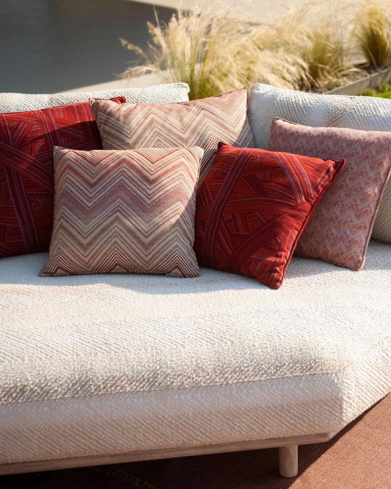 Dalla collezione Roda Missoni: divano Eden in teak e tessuto e cuscini decorativi nei pattern Oper, Spiga e Bamboo nel colore Rust