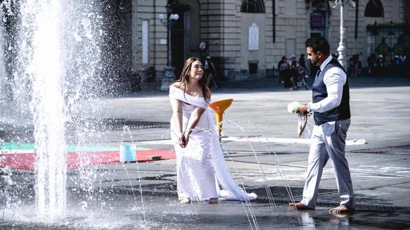 Una coppia di sposi si rinfresca nella fontana di piazza Castello a Torino
