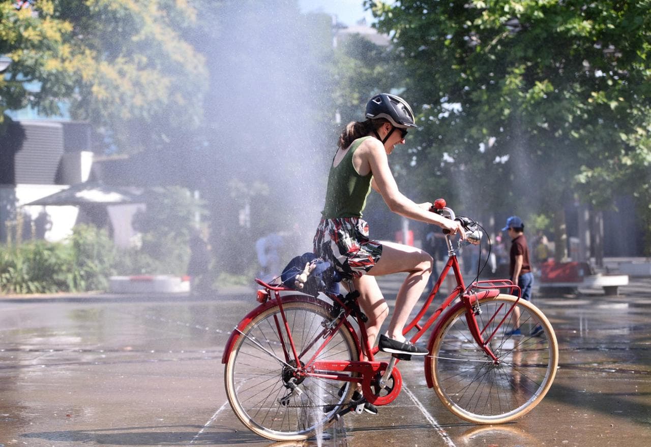 Ondata di caldo a Vienna, in bicicletta ci si rinfresca in un arco acquatico