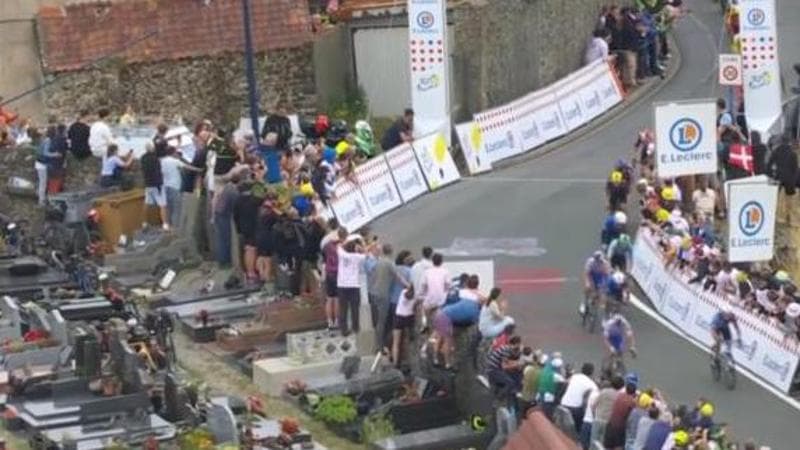 Tifosi in piedi sulle tombe di un cimitero per veder passare il Tour: in Francia è polemica