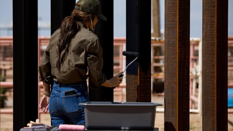 Homeland Security Secretary Kristi Noem paints the steel border wall black after a news conference in Santa Teresa, N.M., on Tuesday, Aug. 19, 2025. She announced the entire structure will be painted black.