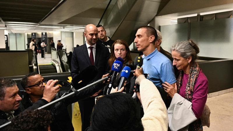 French citizen Camilo Castro (2R), who has been detained in Venezuela since late June, speaks to the press near France's Foreign Affairs Minister Jean-Noel Barrot (C-L) and his mother Helene Castro upon his arrival at Orly aiport, in the outskirts of Paris, following his release on November 16, 2025. Castro, a 41-year-old yoga teacher, disappeared on June 26, 2026 at the Paraguachon border crossing, which separates Venezuela from Colombia, where he lives. He had gone to renew his expired Colombian residency visa, his family said in August. (Photo by MARTIN BUREAU / AFP)