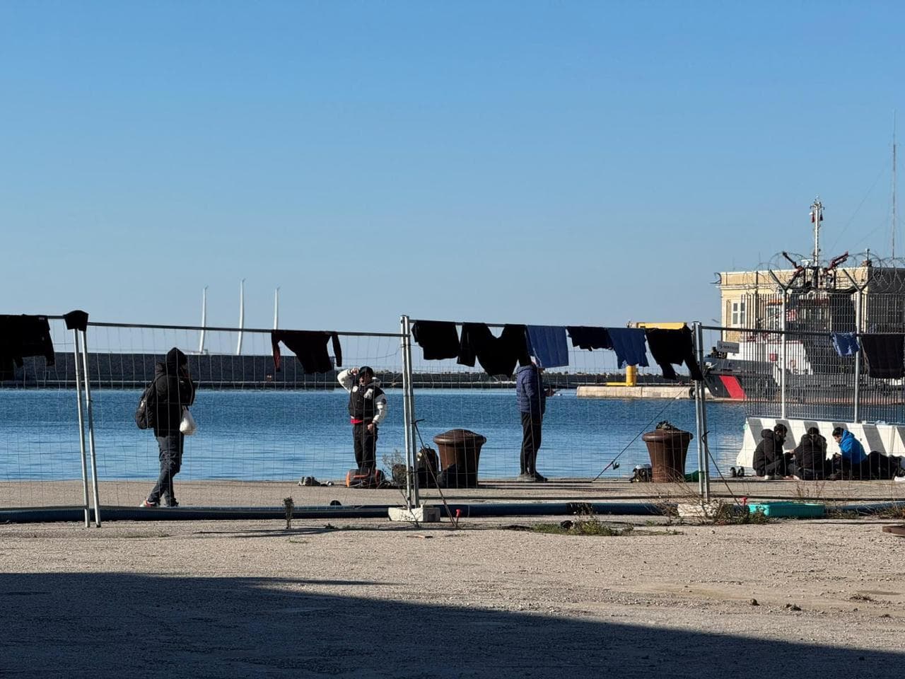 Richiedenti asilo e aspiranti tali sulla banchina nei pressi del magazzino del Porto Vecchio