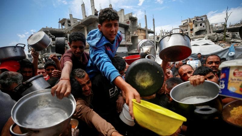 Palestinians wait to receive food cooked by a charity kitchen, in Beit Lahiya, northern Gaza Strip, April 28, 2025. REUTERS/Mahmoud Issa     TPX IMAGES OF THE DAY