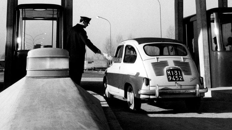 1958, un casellante in divisa mentre riscuote il pedaggio in autostrada
