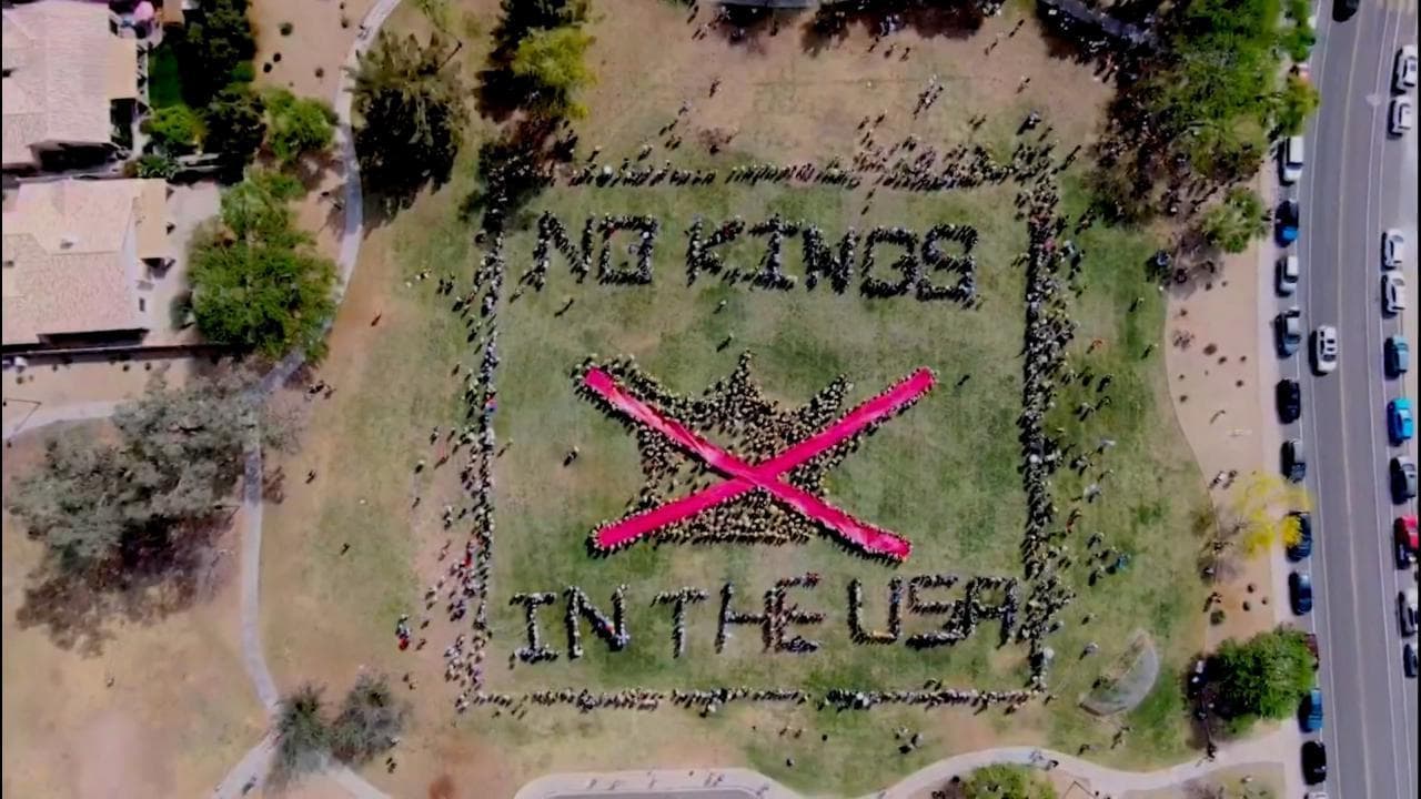 Catena umana crea scritta "No Kings in the Usa" con disegno della corona barrata. La vista dal drone